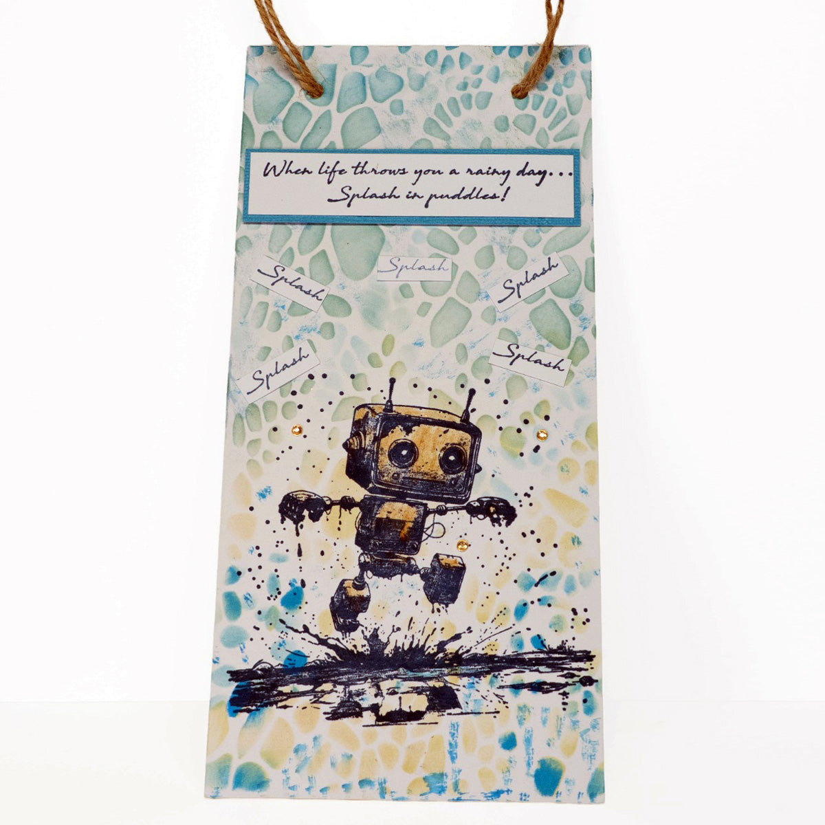 Card with a robot stamp and text saying ''When life throws you a rainy day... splash in a puddle!' with the word 'splash' surrounding the robot on a colorful background