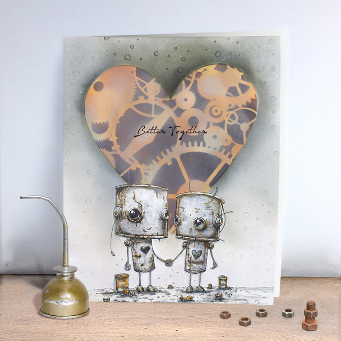 Card with two robots holding hands and a heart-shaped clockwork design above them, with the text 'Better Together'.
