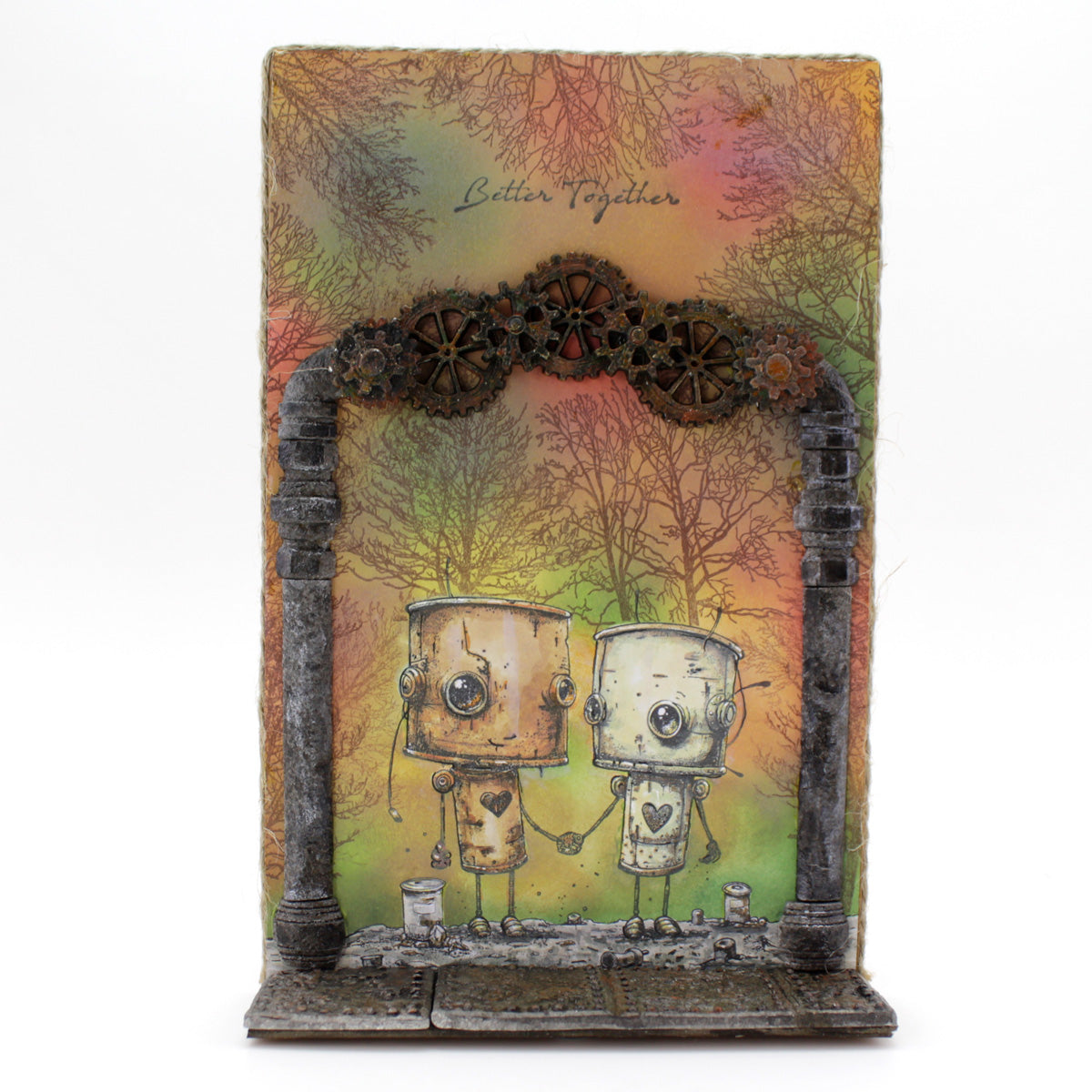 Decorative box with two robot figures holding hands under a pipes and cogs archway, set against a colorful background with the Mould as the flooring.