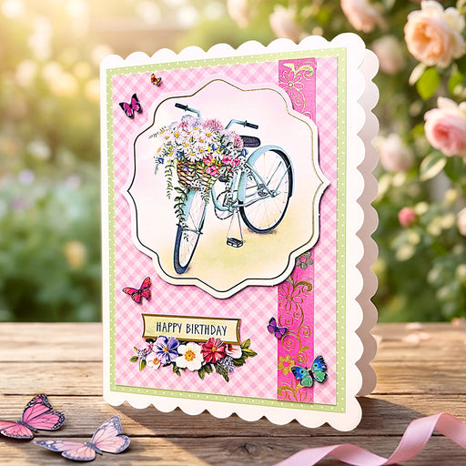 Birthday card with bicycle and flowers design on a pink gingham background, outdoors.