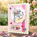 Birthday card with bicycle and flowers design on a pink gingham background, outdoors.
